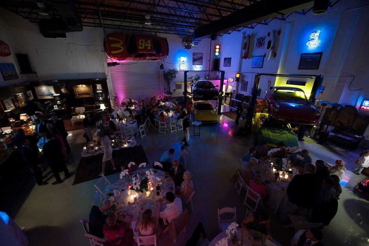 Overhead view of a seated dinner at 51 Club with classic cars glowing on lifts around candlelit tables